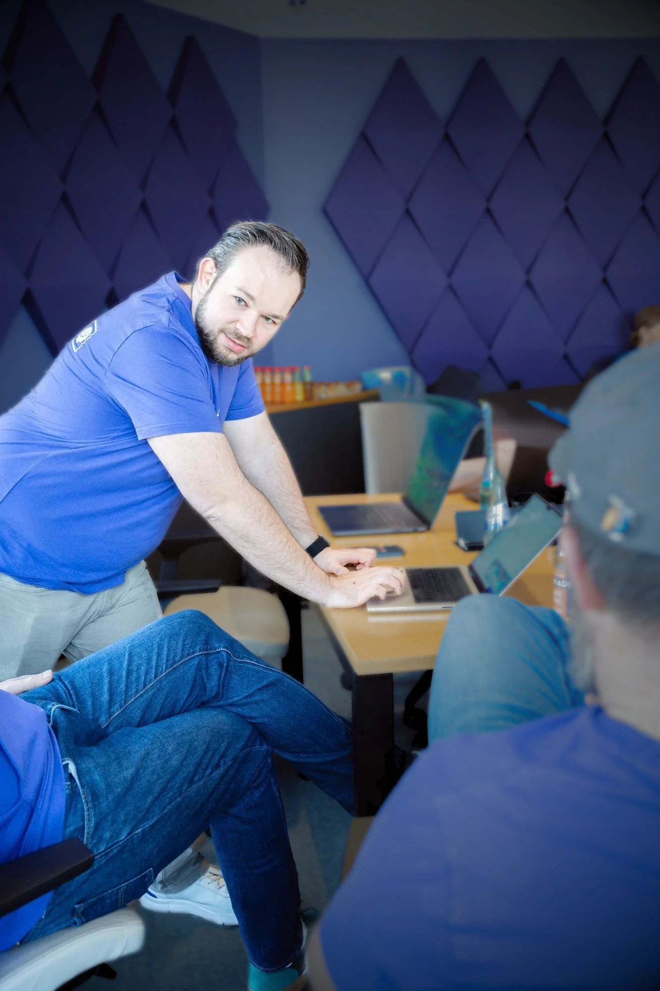 Daniel Rohregger beugt sich bei einem Agenten-Hackathon über einen Tisch mit Laptops und unterstützt Teilnehmende
