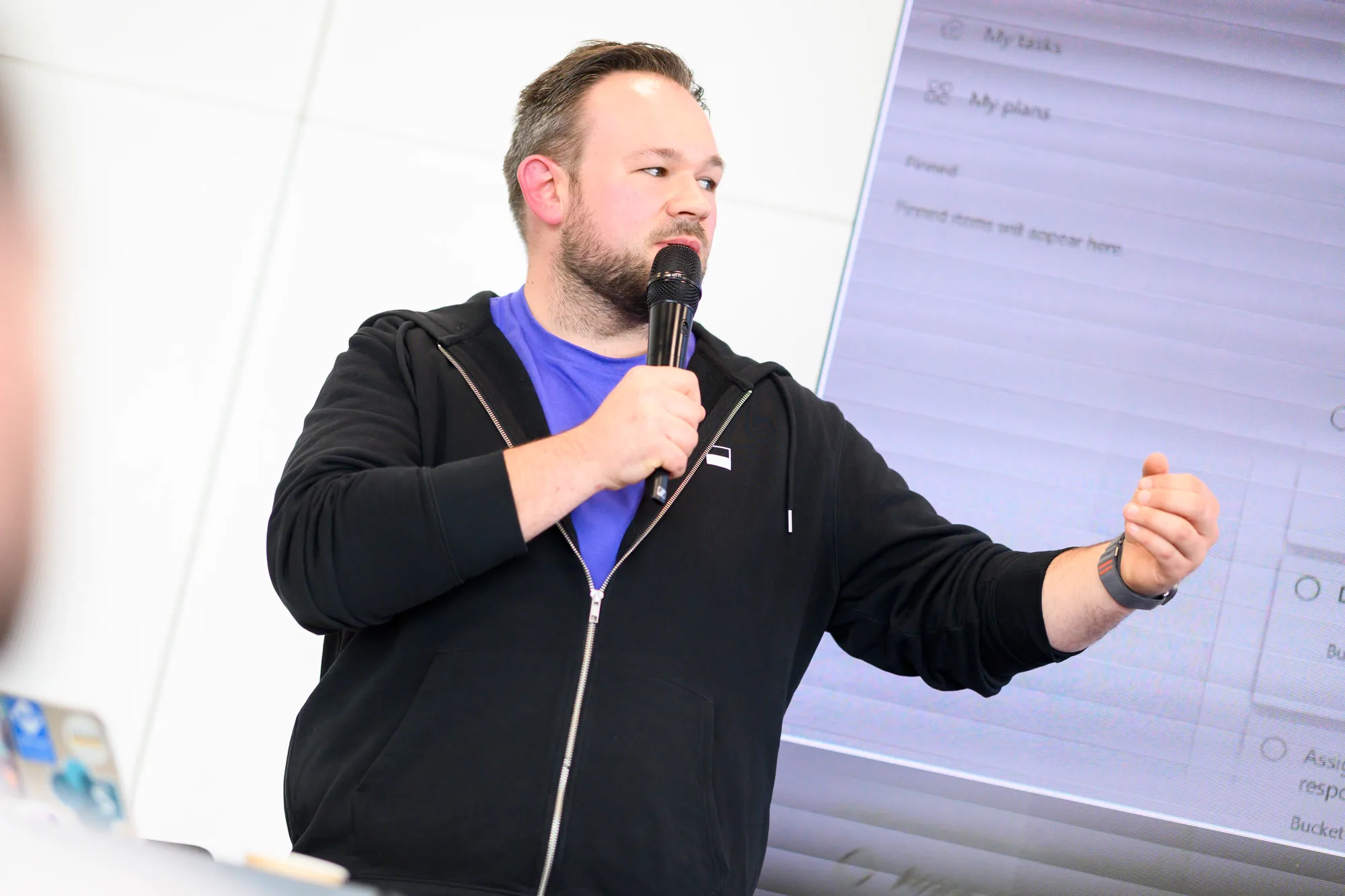 Daniel Rohregger erklärt mit Mikrofon die Aufgabenansicht von Microsoft 365 vor einer Projektion
